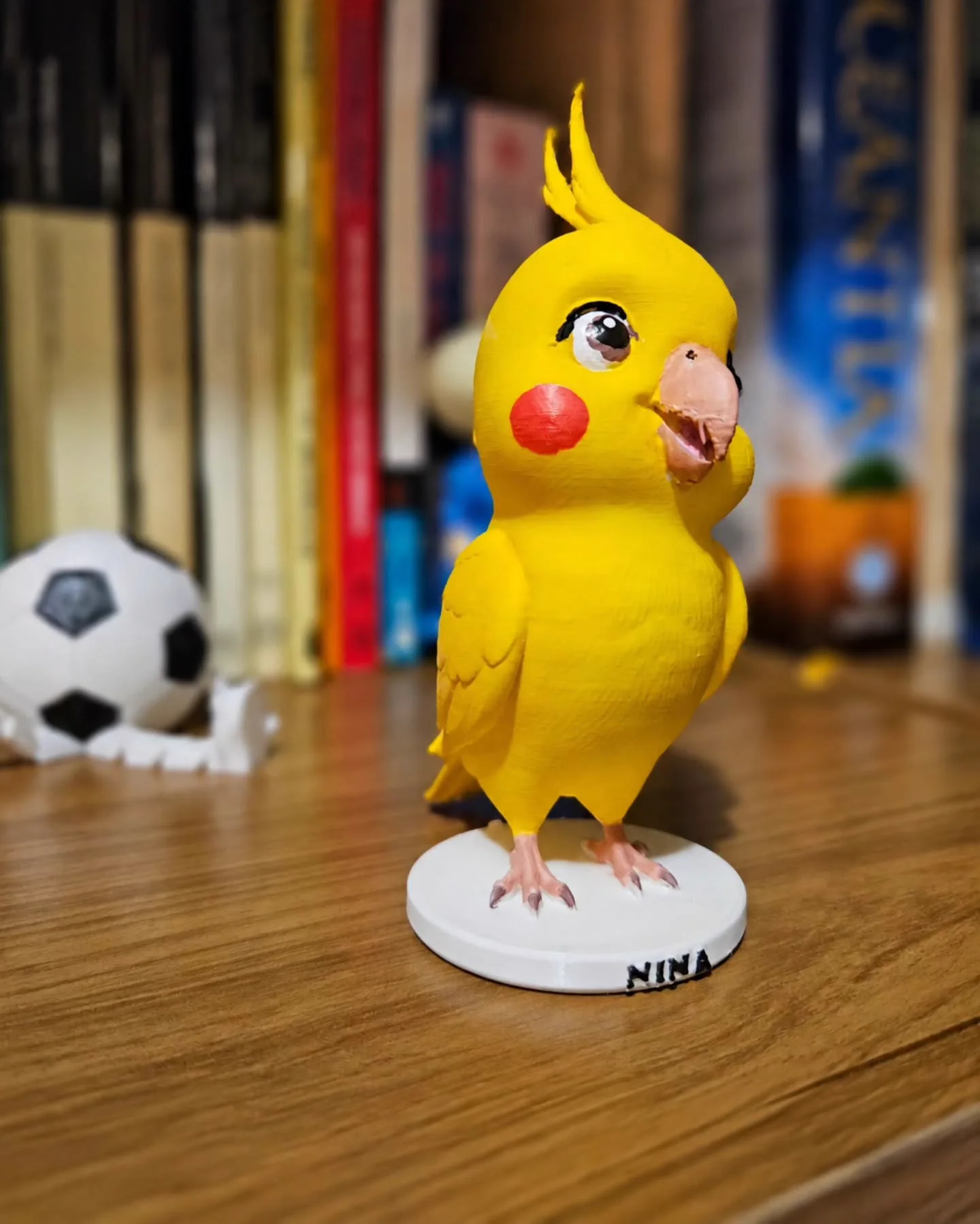Miniatura amarela da calopsita Nina sobre uma base branca